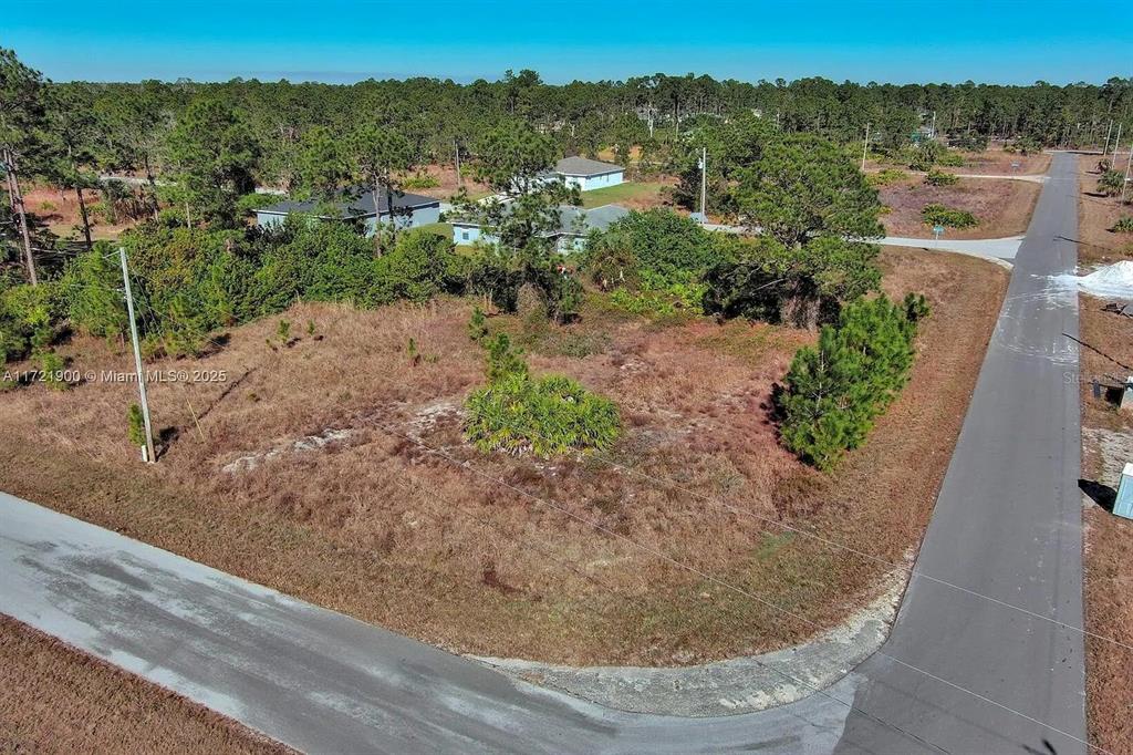 An aerial view of a vacant, grassy corner lot bordered by paved roads — 733 BUMBY STREET E, LEHIGH ACRES, FL