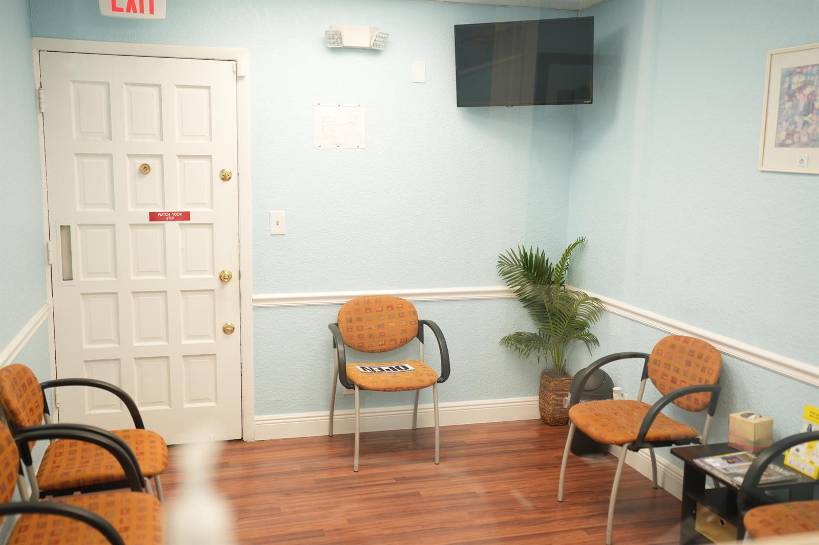 A waiting room with light blue walls, wood-look flooring, and several orange patterned chairs — 2331 N State Rd 7 # 207, Lauderhill FL 33313, LAUDERHILL, FL