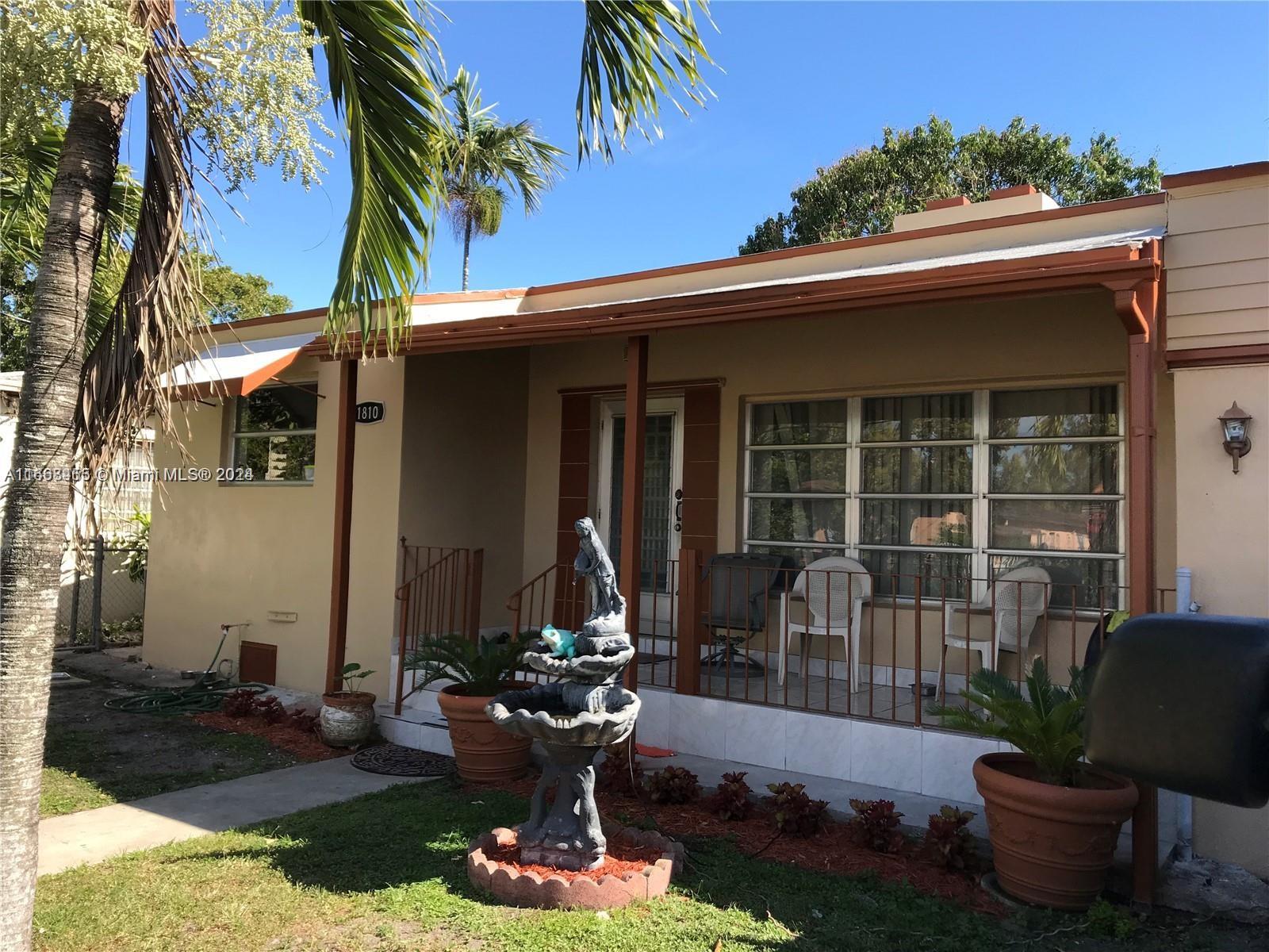 A single-story house features a covered front porch, a tiered fountain, and potted plants — 1810 NW 16th Ter, Miami FL 33125, MIAMI, FL