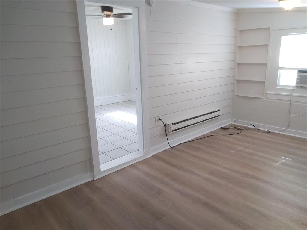 A room with white horizontal wood-paneled walls, light wood flooring, and a doorway to another room — 2609 4TH STREET S UNIT 2, ST PETERSBURG, FL