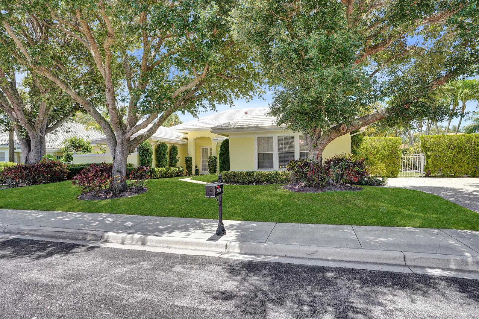 A yellow single-story house with a white roof sits behind a lawn and large trees — 2760 Tecumseh Drive, West Palm Beach FL 33409, WEST PALM BEACH, FL