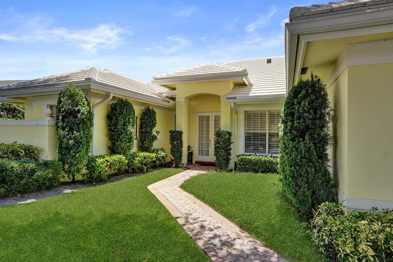 A yellow house features a paved walkway leading to a recessed front entrance with double doors — 2760 Tecumseh Drive, West Palm Beach FL 33409, WEST PALM BEACH, FL