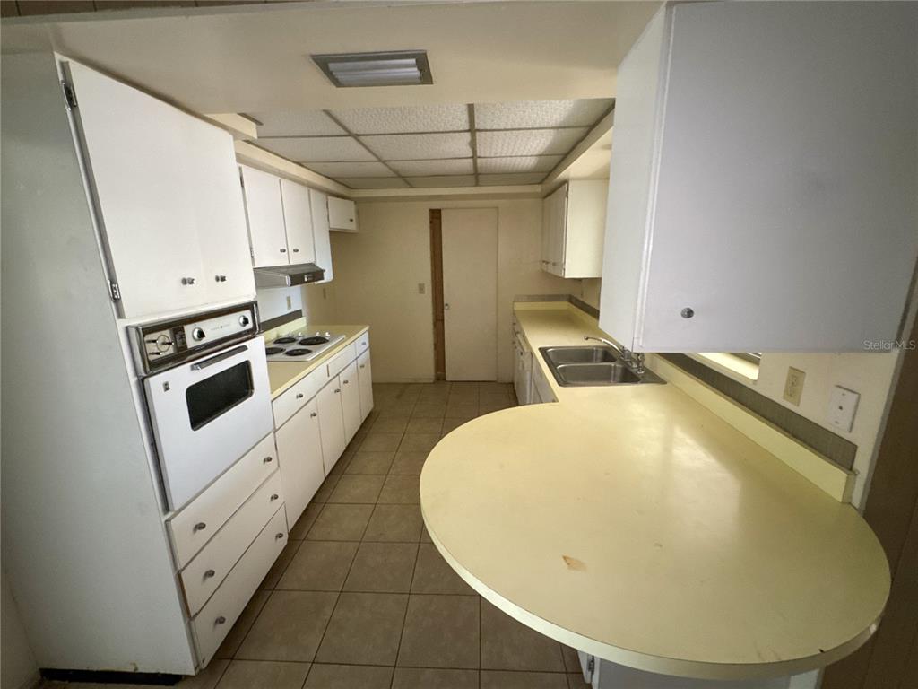 A kitchen features white cabinets, a wall oven, a cooktop, and a curved countertop — 3234 DANTE DRIVE, SARASOTA, FL