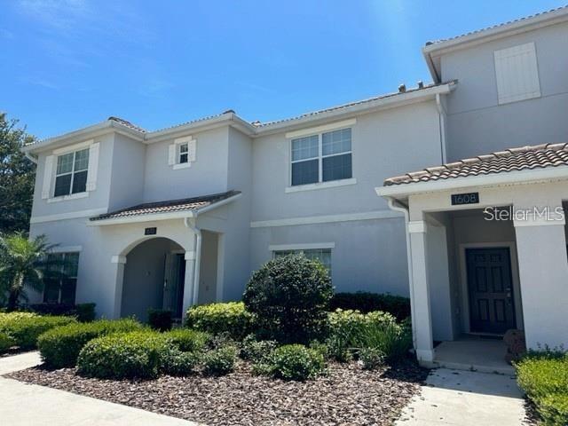 A two-story light-colored townhouse features a tiled roof and a covered entryway — 1608 MOON VALLEY DRIVE, DAVENPORT, FL