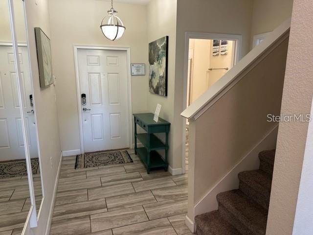 An entryway features a white front door, a teal console table, and carpeted stairs — 1608 MOON VALLEY DRIVE, DAVENPORT, FL