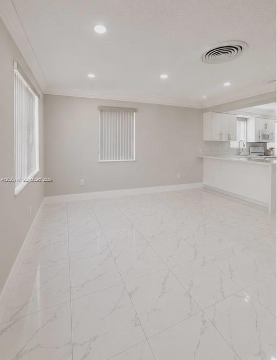 A bright room with white marble-patterned tile flooring, recessed lighting, and an open kitchen area — 5735 Hayes St, Hollywood FL 33021, HOLLYWOOD, FL