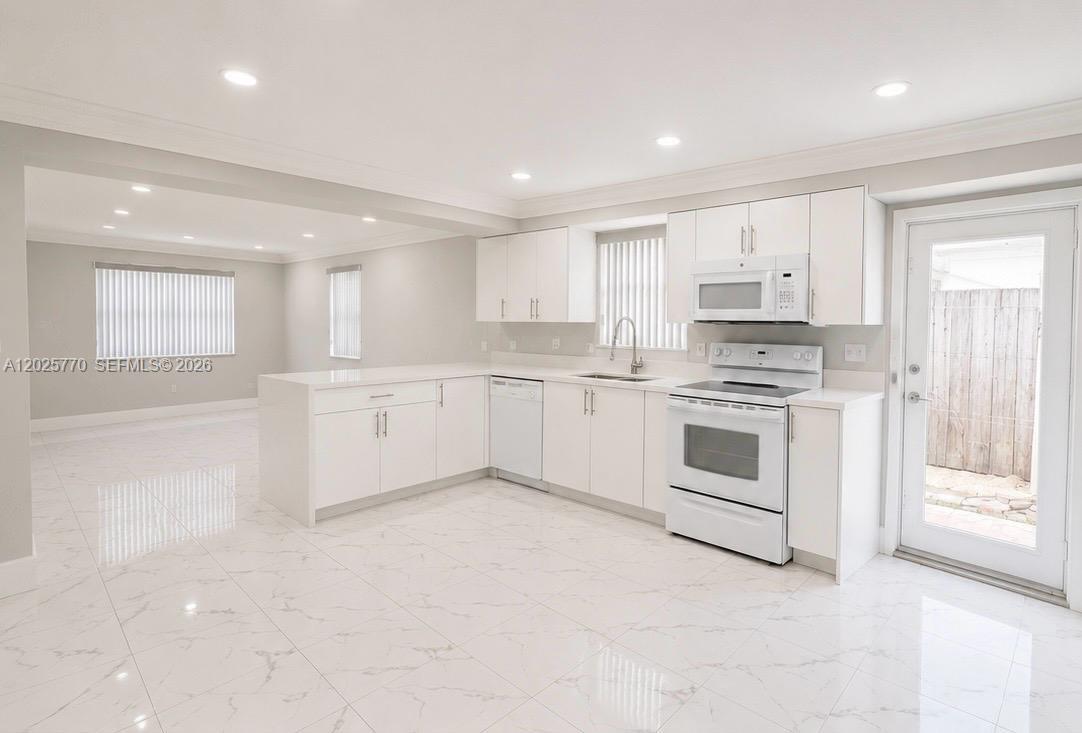 A white kitchen features marble-look tile flooring, modern cabinetry, and stainless steel appliances — 5735 Hayes St, Hollywood FL 33021, HOLLYWOOD, FL