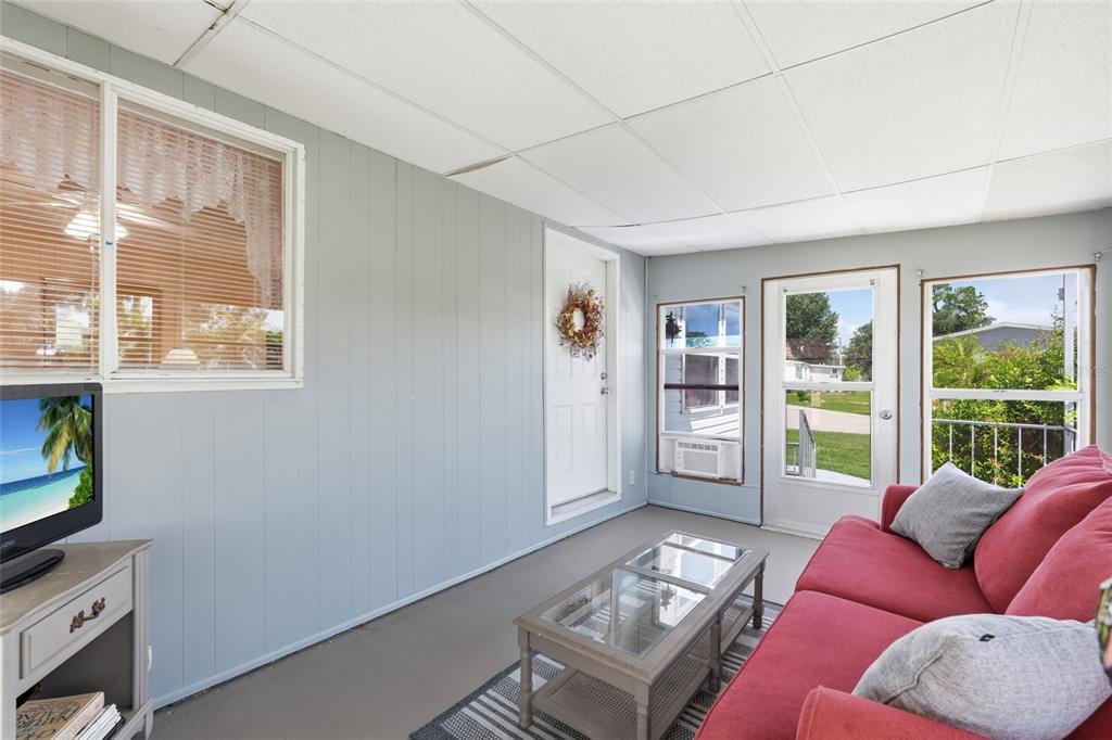 A sunroom features light blue paneled walls, a red sofa, and a glass-topped coffee table — 5058 PALENA BOULEVARD, NORTH PORT, FL