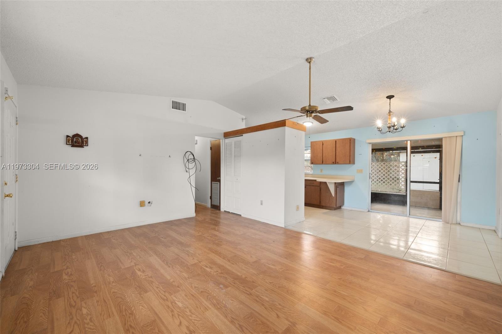 A living room with wood-look flooring transitions to a tiled dining area and kitchen — 2067 N Terrapin Road, Avon Park FL 33825, AVON PARK, FL