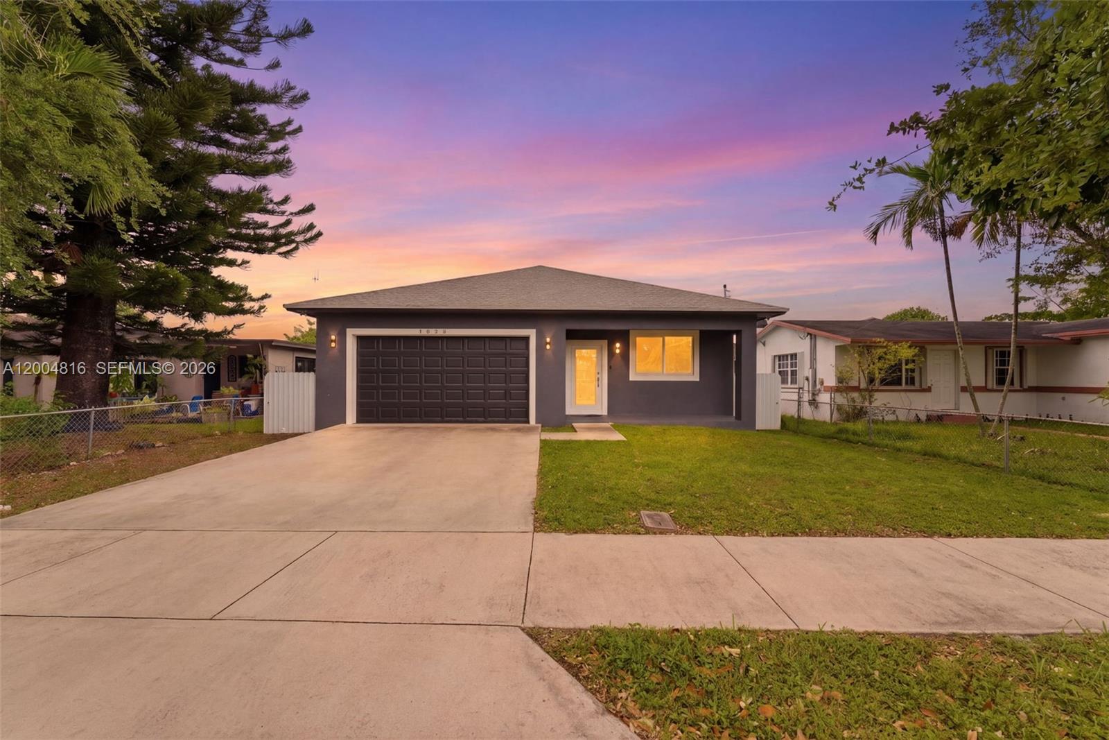 A gray single-story house with a garage and a concrete driveway at sunset — 5628 Flagler St, Hollywood FL 33023, HOLLYWOOD, FL