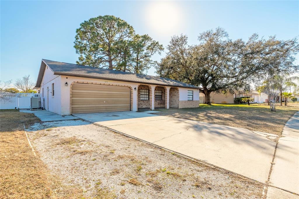 A single-story house with a two-car garage, arched entryway, and a concrete driveway — 1210 MELLISA DRIVE, PORT ORANGE, FL