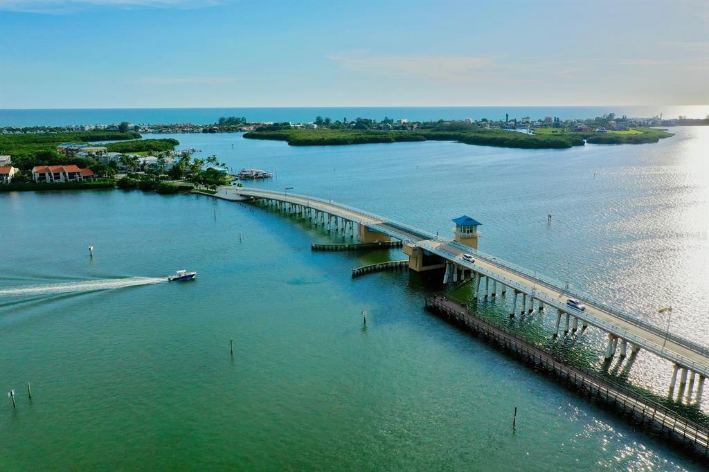 An aerial view of a bridge spanning a waterway with a boat passing underneath — 3420 SARTO LANE, ROTONDA WEST, FL