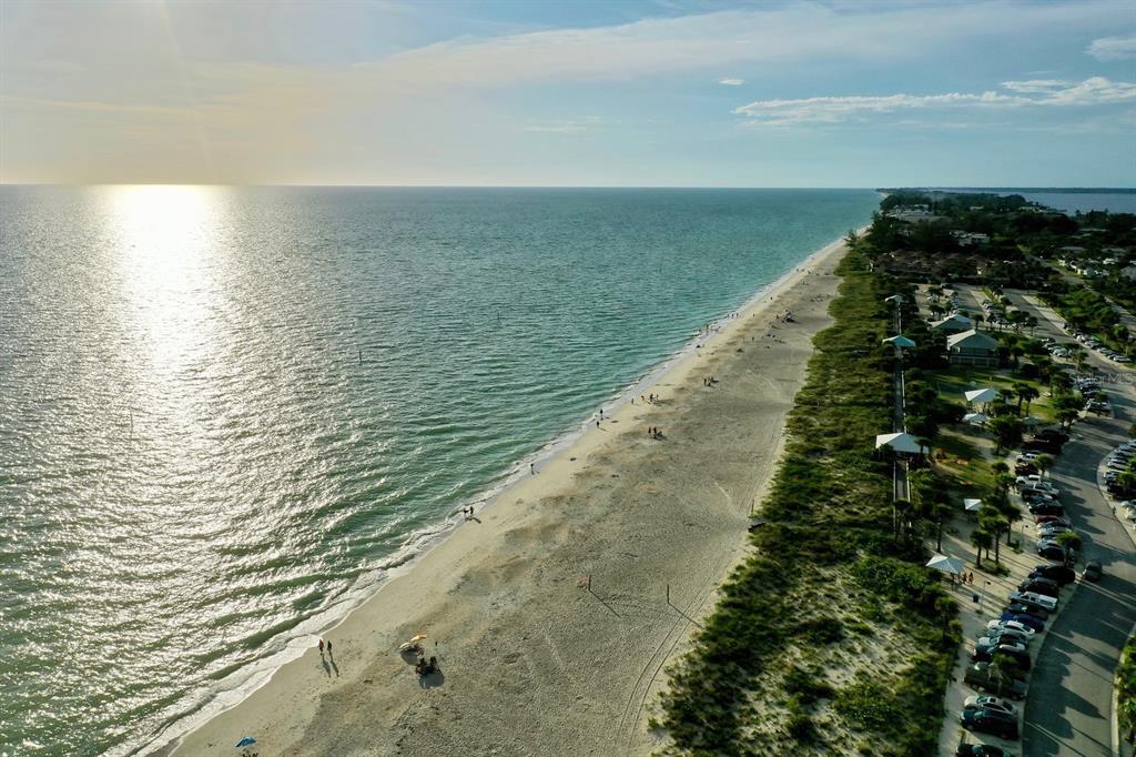 An aerial view of a sandy beach coastline with a parking lot and vegetation nearby — 3420 SARTO LANE, ROTONDA WEST, FL