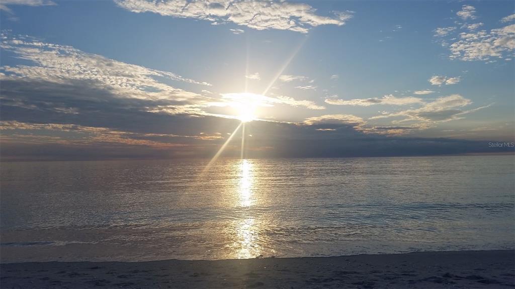 A bright sun shines over the ocean at sunset with a sandy beach in the foreground — 3420 SARTO LANE, ROTONDA WEST, FL