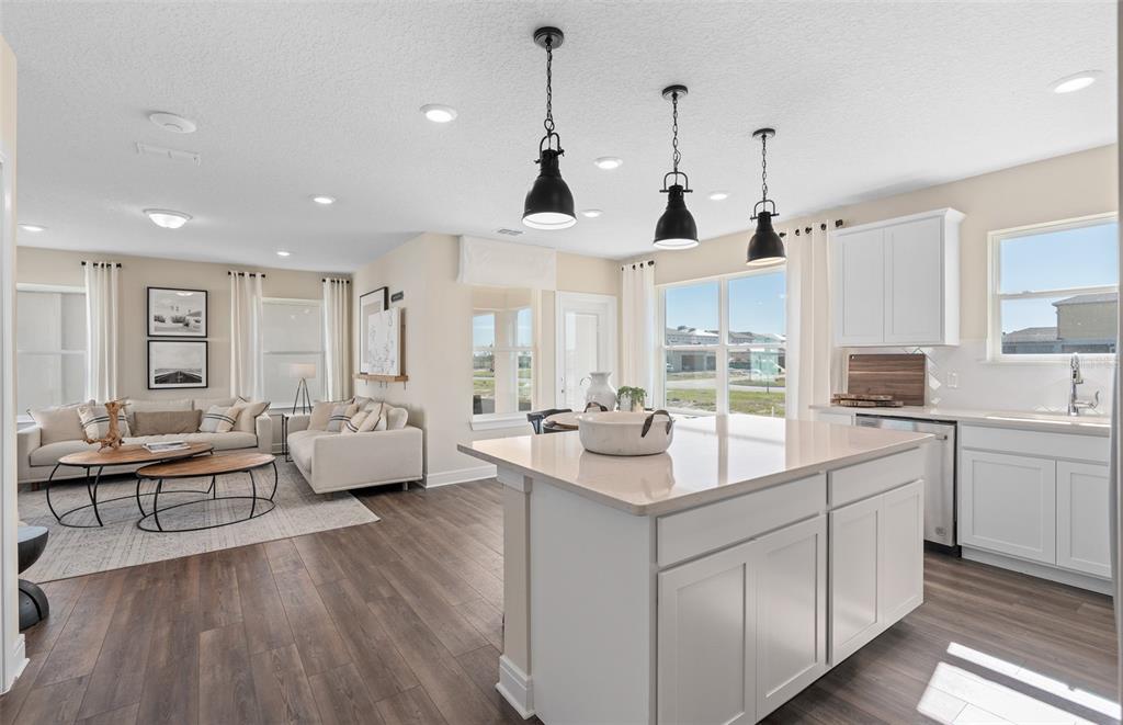 A modern open-concept kitchen and living area featuring white cabinetry, a central island, and flooring — 2644 CLEAR NIGHT AVENUE DRIVE, KISSIMMEE, FL