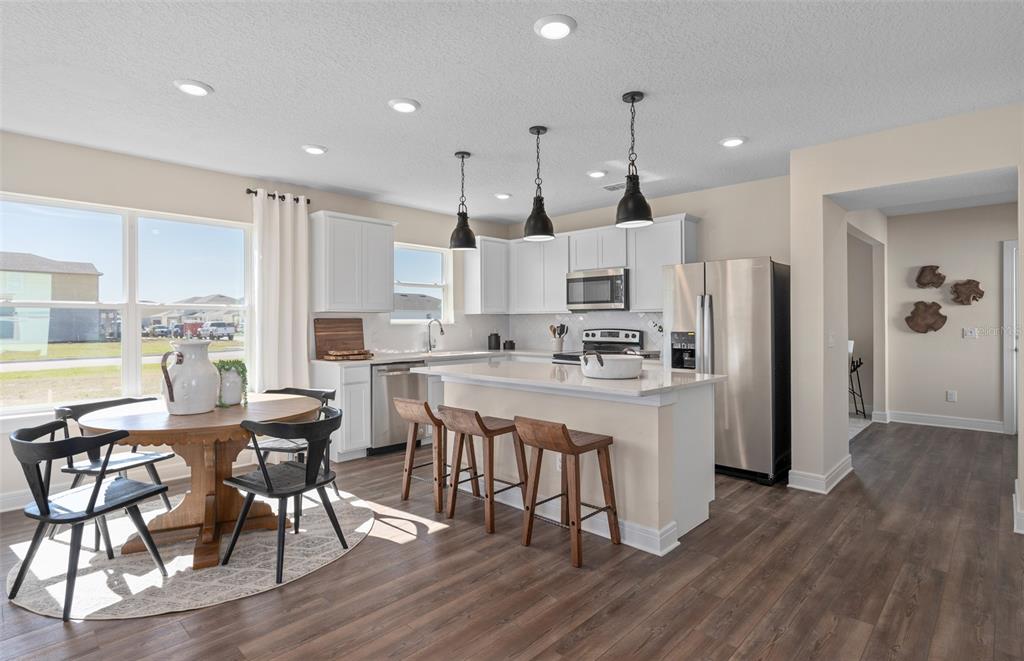 A kitchen and dining area feature white cabinets, a central island, and wood-look flooring — 2644 CLEAR NIGHT AVENUE DRIVE, KISSIMMEE, FL