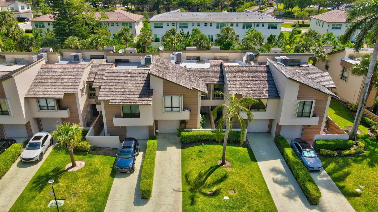 An aerial view of a multi-unit townhouse complex with driveways, green lawns, and palm trees — 22922 Ironwedge Drive, Boca Raton FL 33433, BOCA RATON, FL