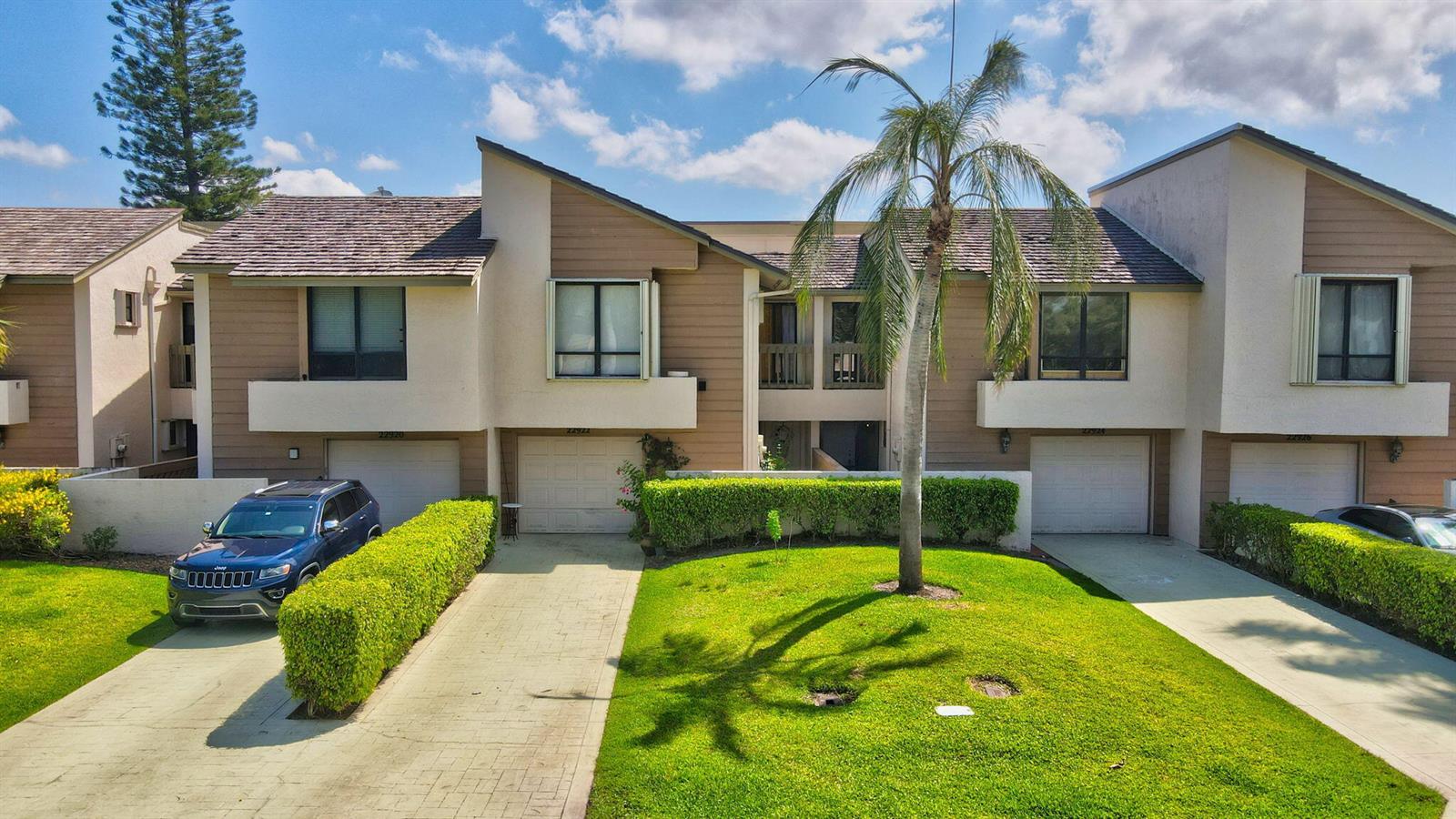 A row of multi-story townhomes with beige siding, shingled roofs, and attached garages — 22922 Ironwedge Drive, Boca Raton FL 33433, BOCA RATON, FL