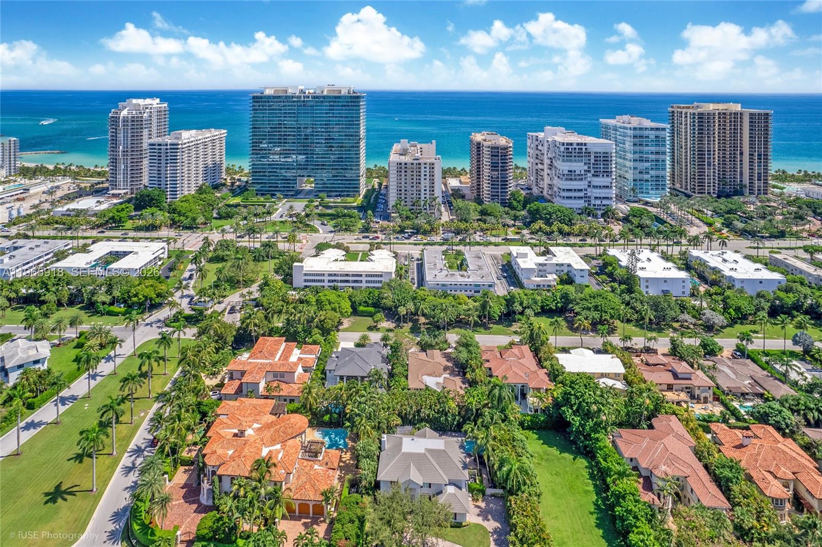 A grassy lawn leads to a gated community entrance with palm trees and a guardhouse — 52 Camden Dr, Bal Harbour FL 33154, BAL HARBOUR, FL