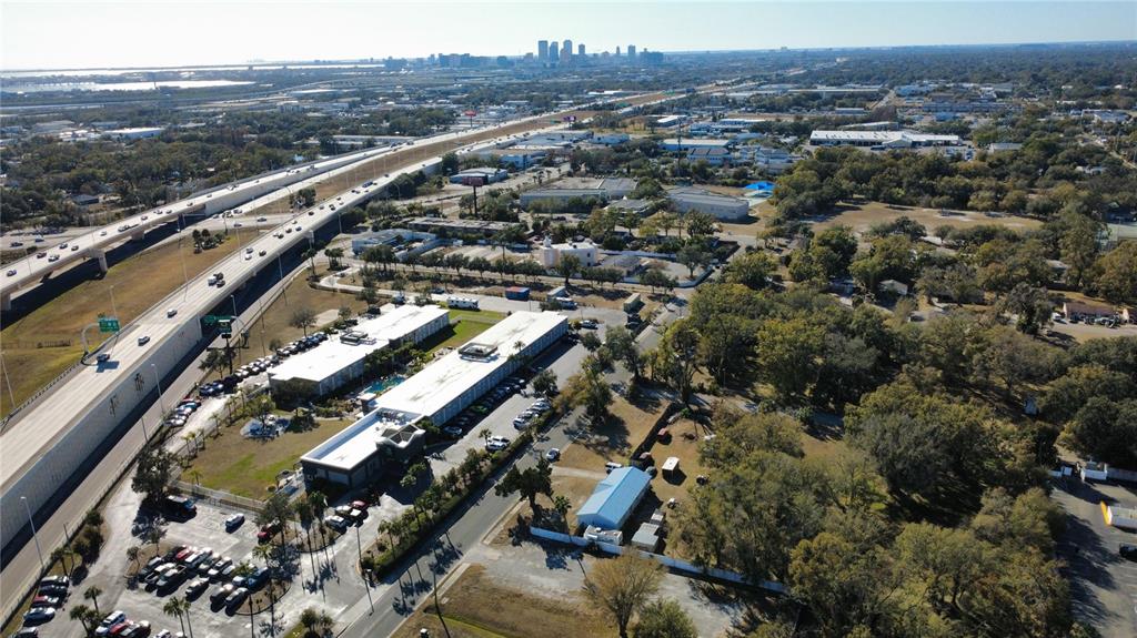 An aerial view shows a hotel complex next to a highway with a city skyline — 4902 E 18TH AVENUE, TAMPA, FL