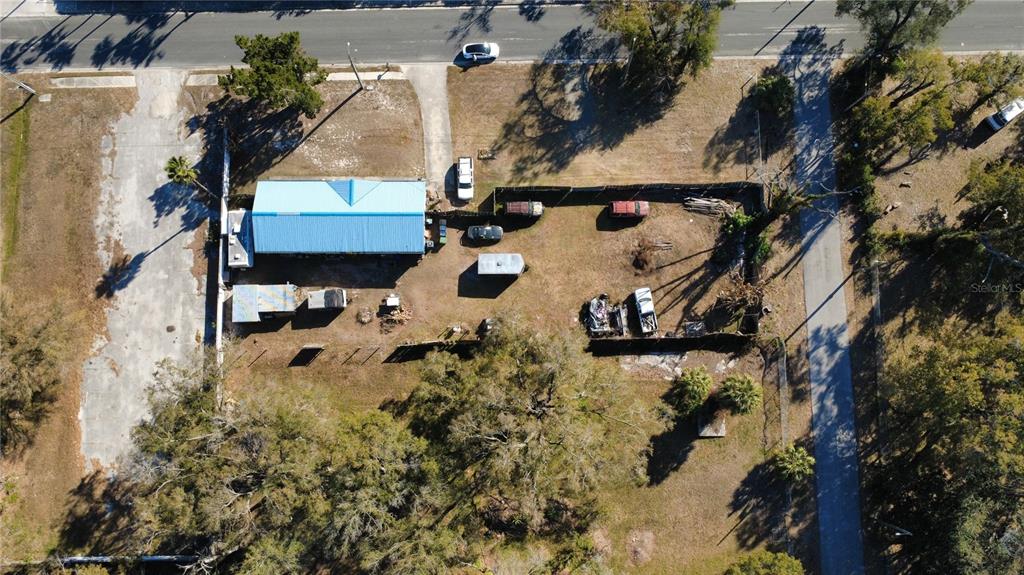 An aerial view shows a house with a blue roof, a fenced yard, and vehicles — 4902 E 18TH AVENUE, TAMPA, FL