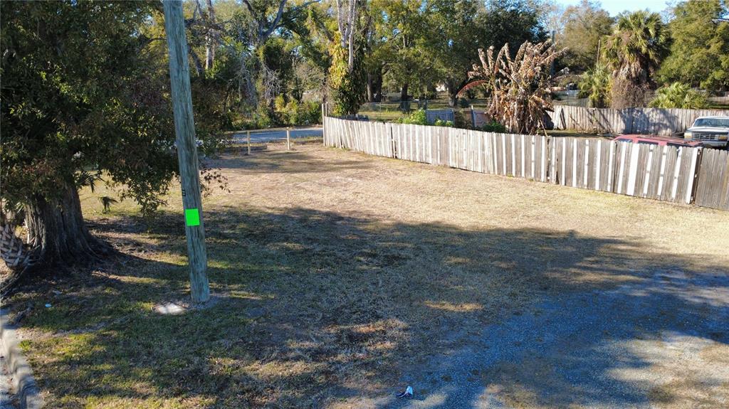 An empty, grassy residential lot features a wooden fence and a large tree — 4902 E 18TH AVENUE, TAMPA, FL