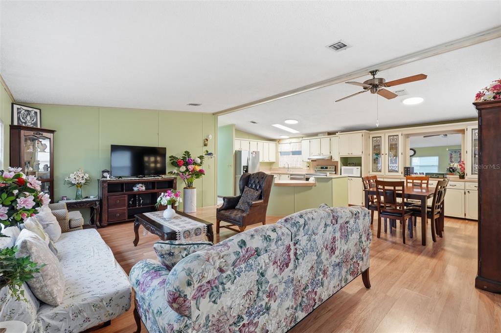 An open-concept living room and kitchen feature light green walls and wood-look flooring — 5027 FOREST CREST DRIVE, LAKELAND, FL