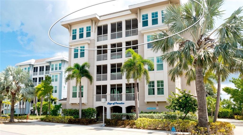 A multi-story residential building with screened balconies and palm trees in front — 395 ARUBA CIRCLE UNIT 401, BRADENTON, FL