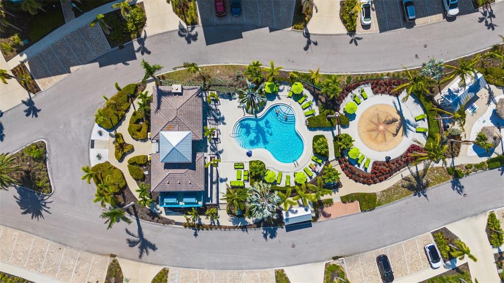 An aerial view shows a community pool area with a clubhouse, lounge chairs, and landscaping — 395 ARUBA CIRCLE UNIT 401, BRADENTON, FL