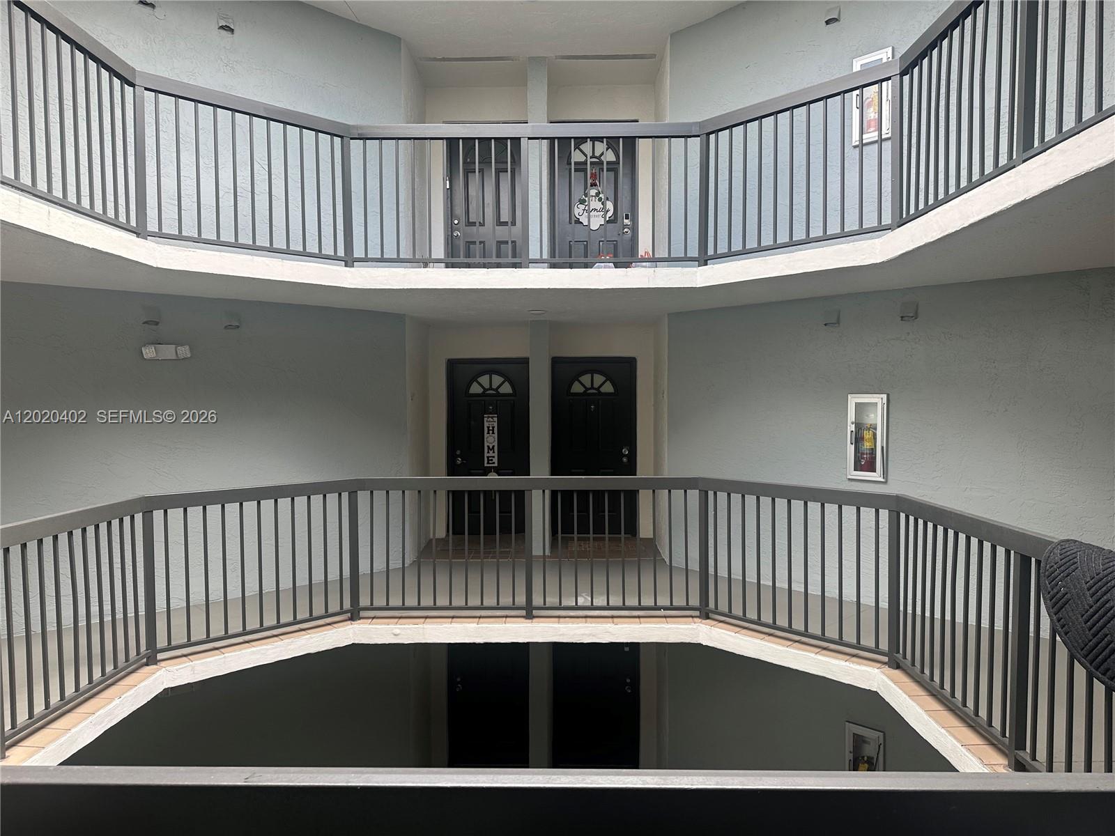 An open-air apartment building atrium features two levels of walkways with dark railings — 6272 NW 186th St # 212, Hialeah FL 33015, HIALEAH, FL