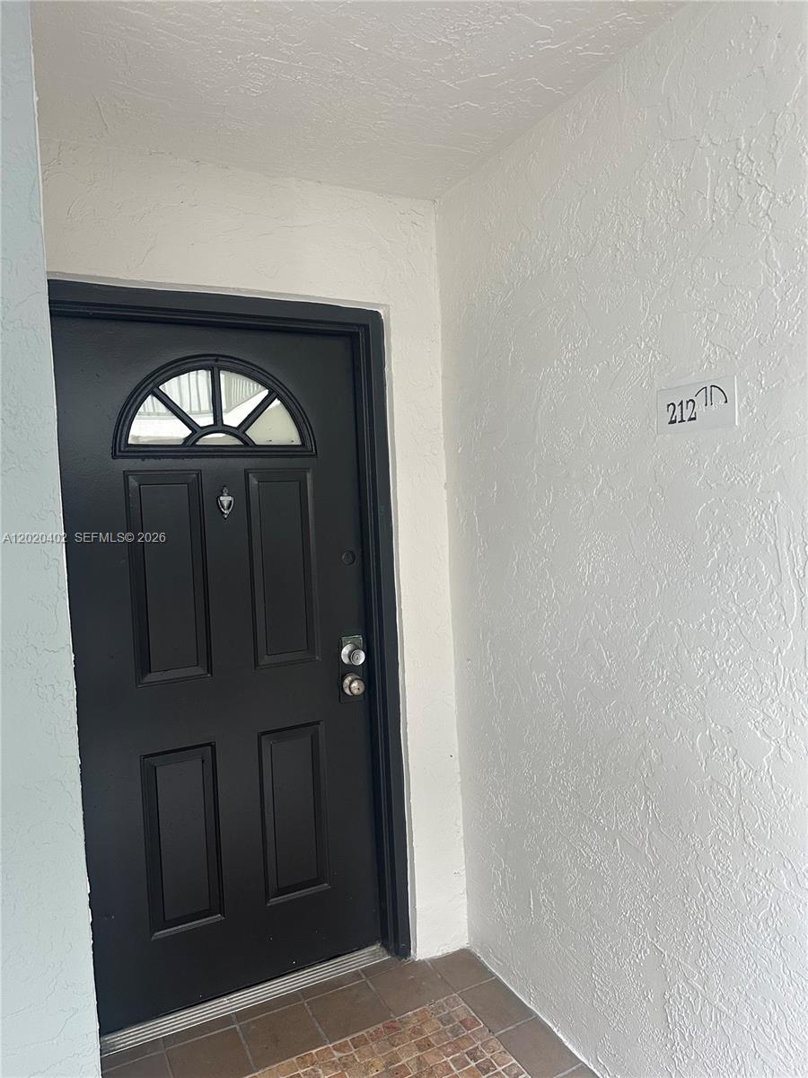 A black front door with a small arched window is set into a white wall — 6272 NW 186th St # 212, Hialeah FL 33015, HIALEAH, FL
