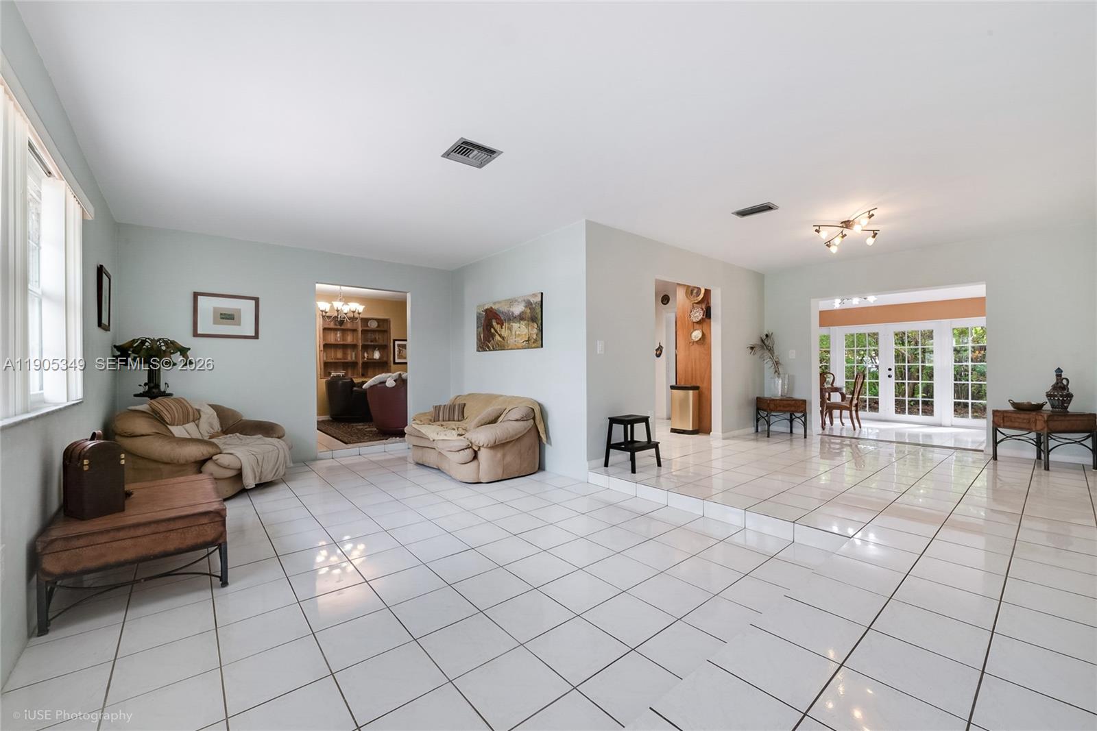 A living room features white tiled floors, a sunken seating area, and French doors — 9500 SW 79th St, Miami FL 33173, MIAMI, FL