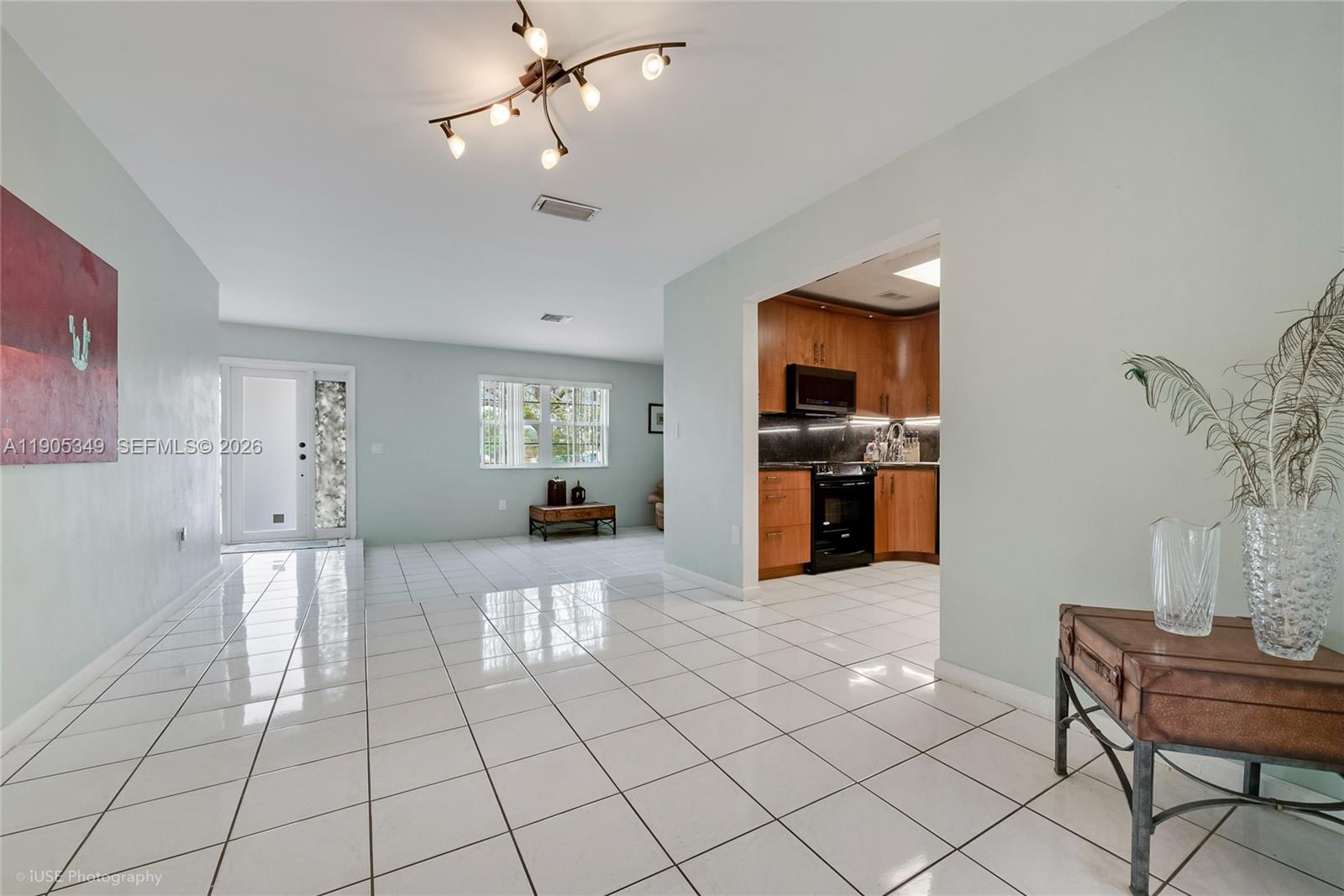 A bright, open-concept living area features white tile flooring, light green walls, and a kitchen — 9500 SW 79th St, Miami FL 33173, MIAMI, FL
