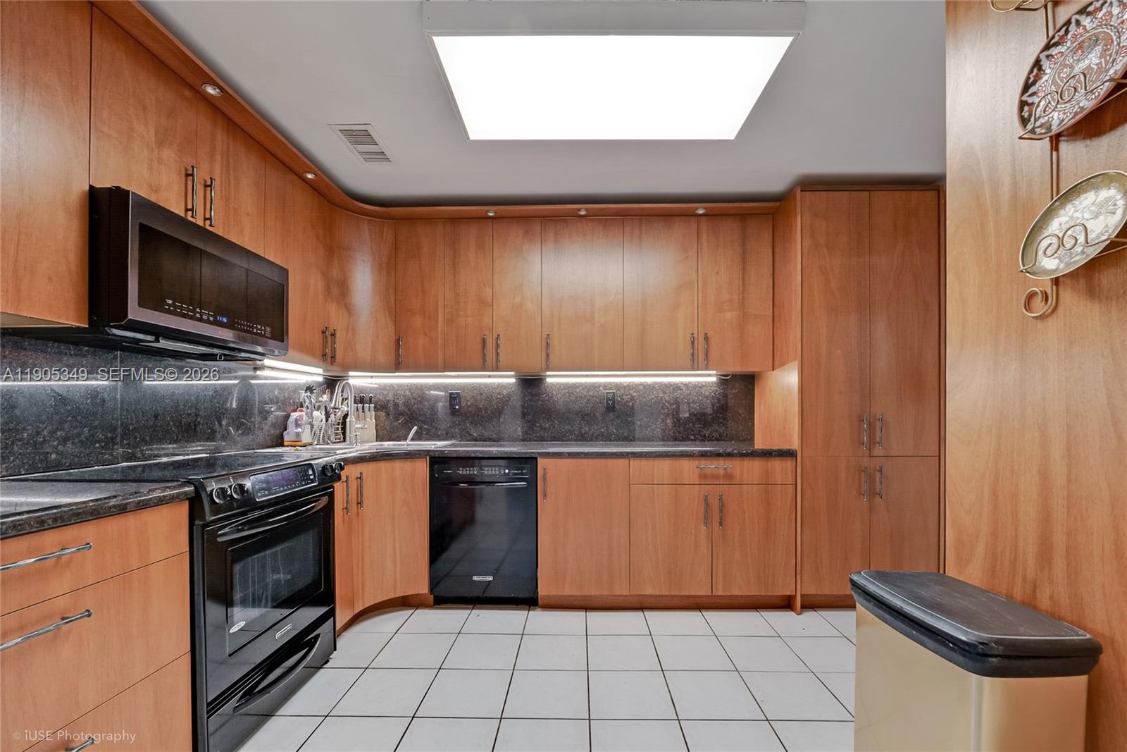 A kitchen features wood cabinets, black appliances, dark countertops, and white tiled flooring — 9500 SW 79th St, Miami FL 33173, MIAMI, FL