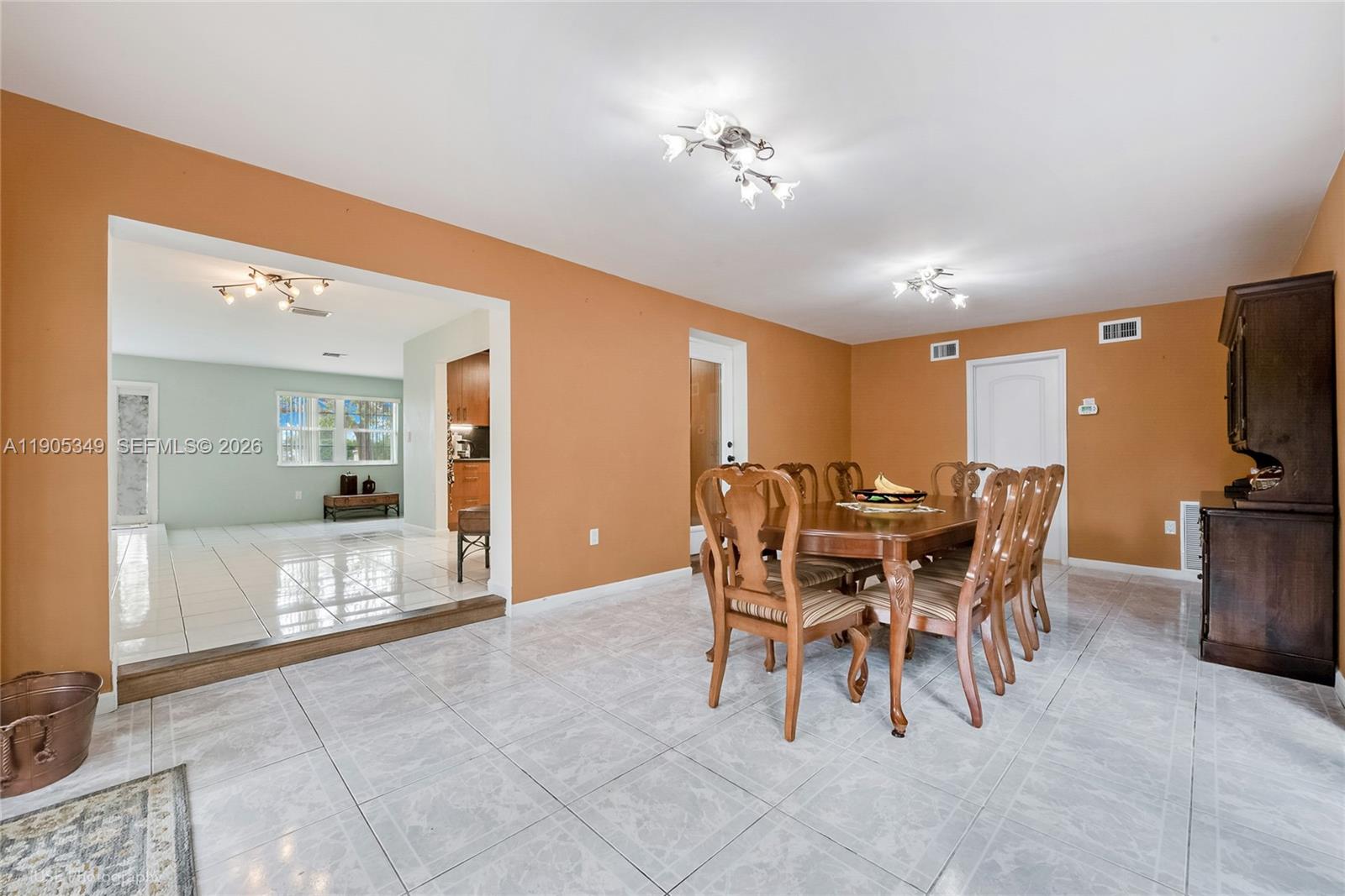 A dining room with tile floors and orange walls connects to an adjacent living area — 9500 SW 79th St, Miami FL 33173, MIAMI, FL