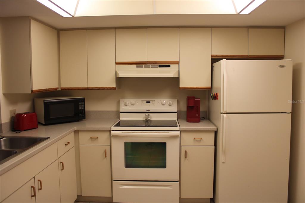 A kitchen features white cabinets, white appliances, and light-colored countertops — 6304 POINTE WEST BOULEVARD UNIT A309, BRADENTON, FL