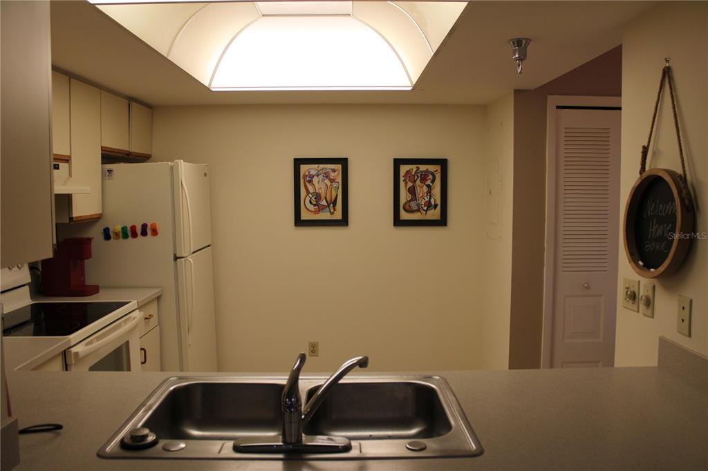 A kitchen features a double-basin sink, white appliances, light-colored cabinets, and two framed wall pictures — 6304 POINTE WEST BOULEVARD UNIT A309, BRADENTON, FL
