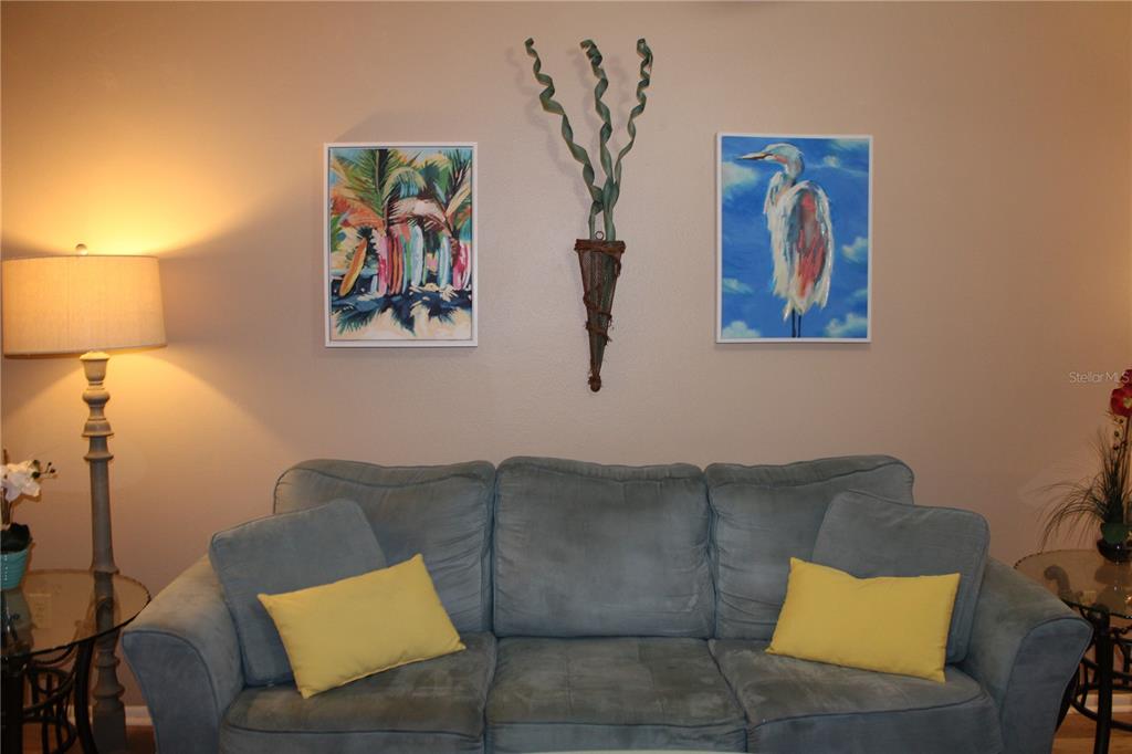 A blue sofa sits against a wall decorated with two framed prints and a wall hanging — 6304 POINTE WEST BOULEVARD UNIT A309, BRADENTON, FL