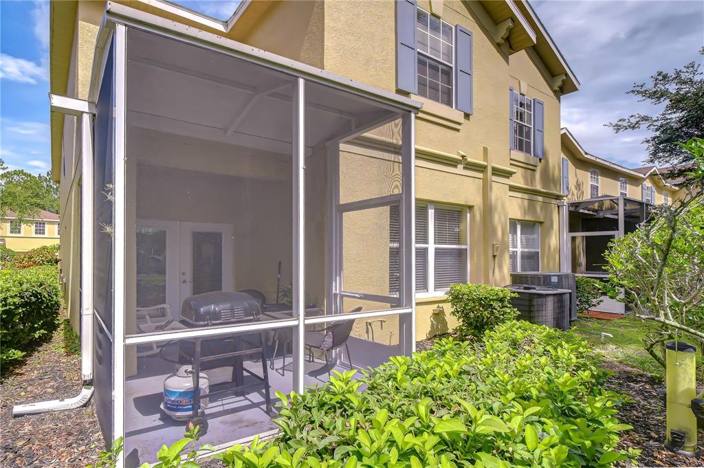 A screened-in patio with a grill sits beside a two-story yellow stucco house — 9328 STONE RIVER PLACE, RIVERVIEW, FL