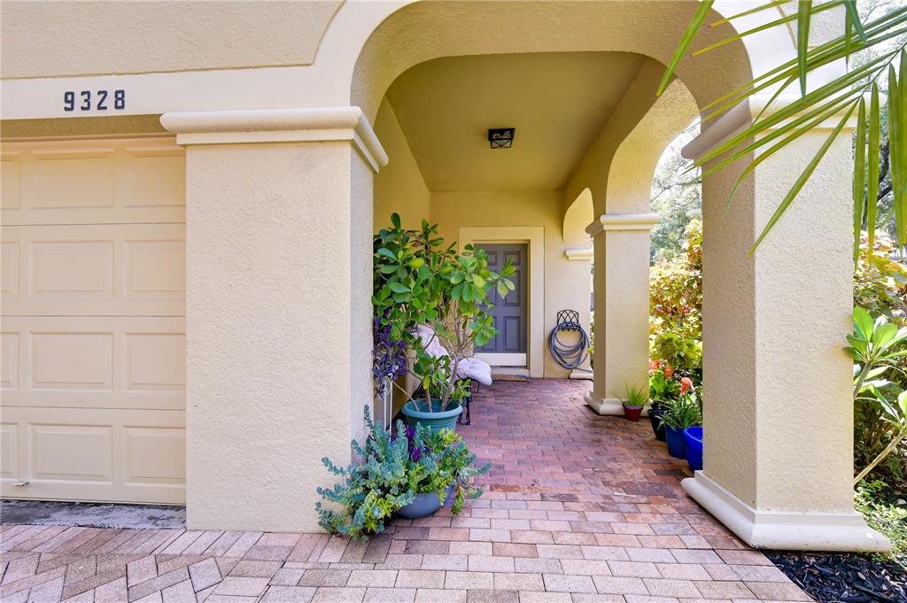 A covered brick entryway leads to a front door with potted plants and columns — 9328 STONE RIVER PLACE, RIVERVIEW, FL