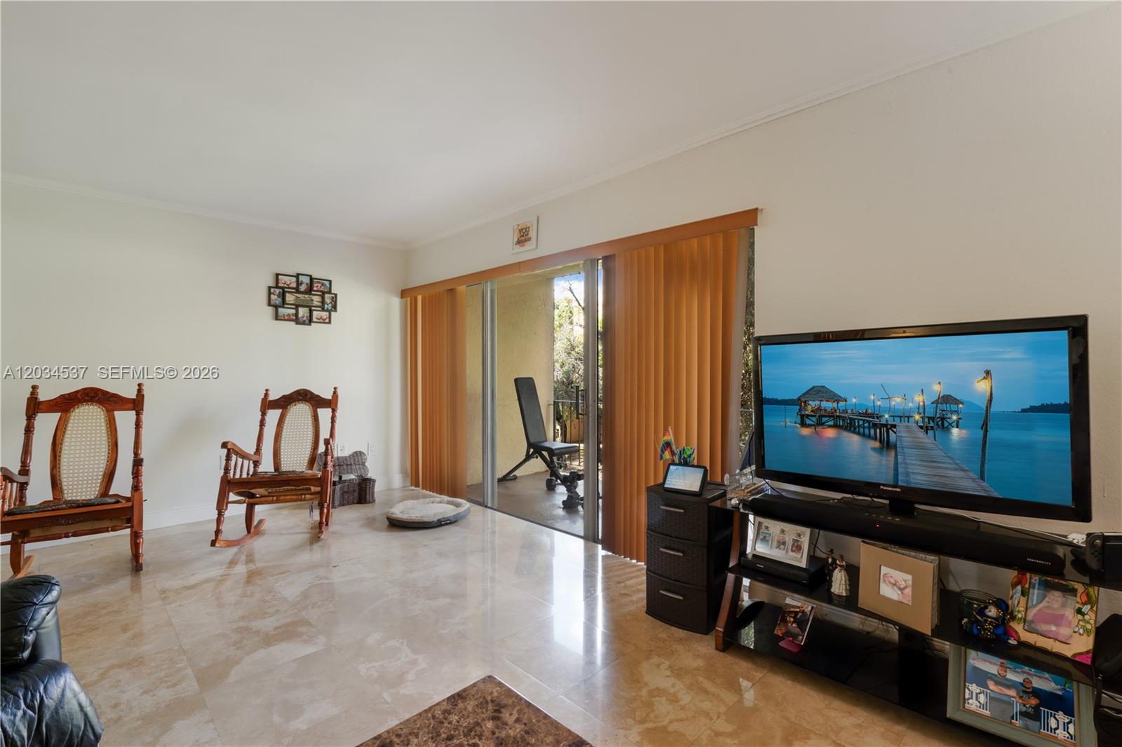 A living room features tile floors, a television, a rocking chair, and a sliding glass door — 9371 Fontainebleau Blvd # I204, Miami FL 33172, MIAMI, FL