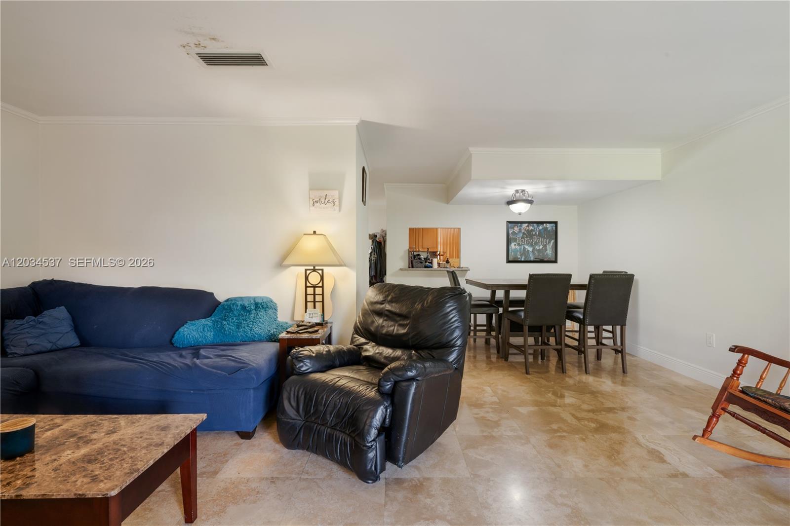 A living room with a blue sofa, black recliner, and dining area on tile floors — 9371 Fontainebleau Blvd # I204, Miami FL 33172, MIAMI, FL