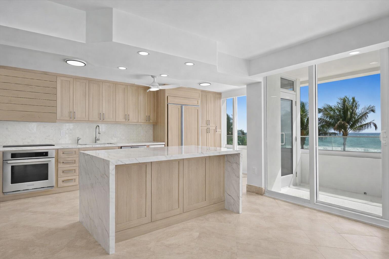 A modern kitchen with light wood cabinets, a marble island, and a balcony overlooking the ocean — 2800 S Ocean Boulevard Unit 2f, Boca Raton FL 33432, BOCA RATON, FL