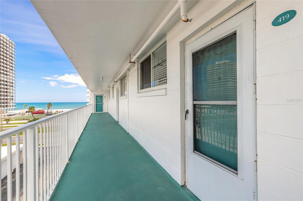 An outdoor balcony walkway with white railings, a green floor, and unit doors — 2727 N ATLANTIC AVENUE UNIT 4190, DAYTONA BEACH, FL