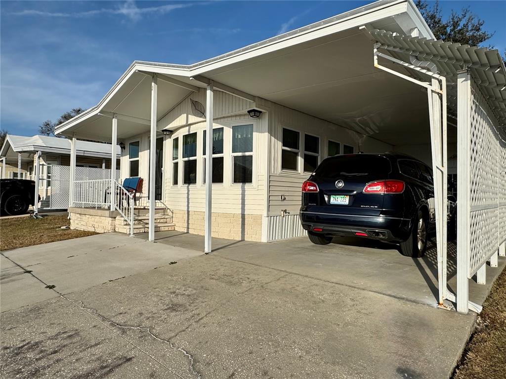 A mobile home with a carport, a concrete driveway, and a small front porch — 4920 BRITNI WAY UNIT 074, ZEPHYRHILLS, FL