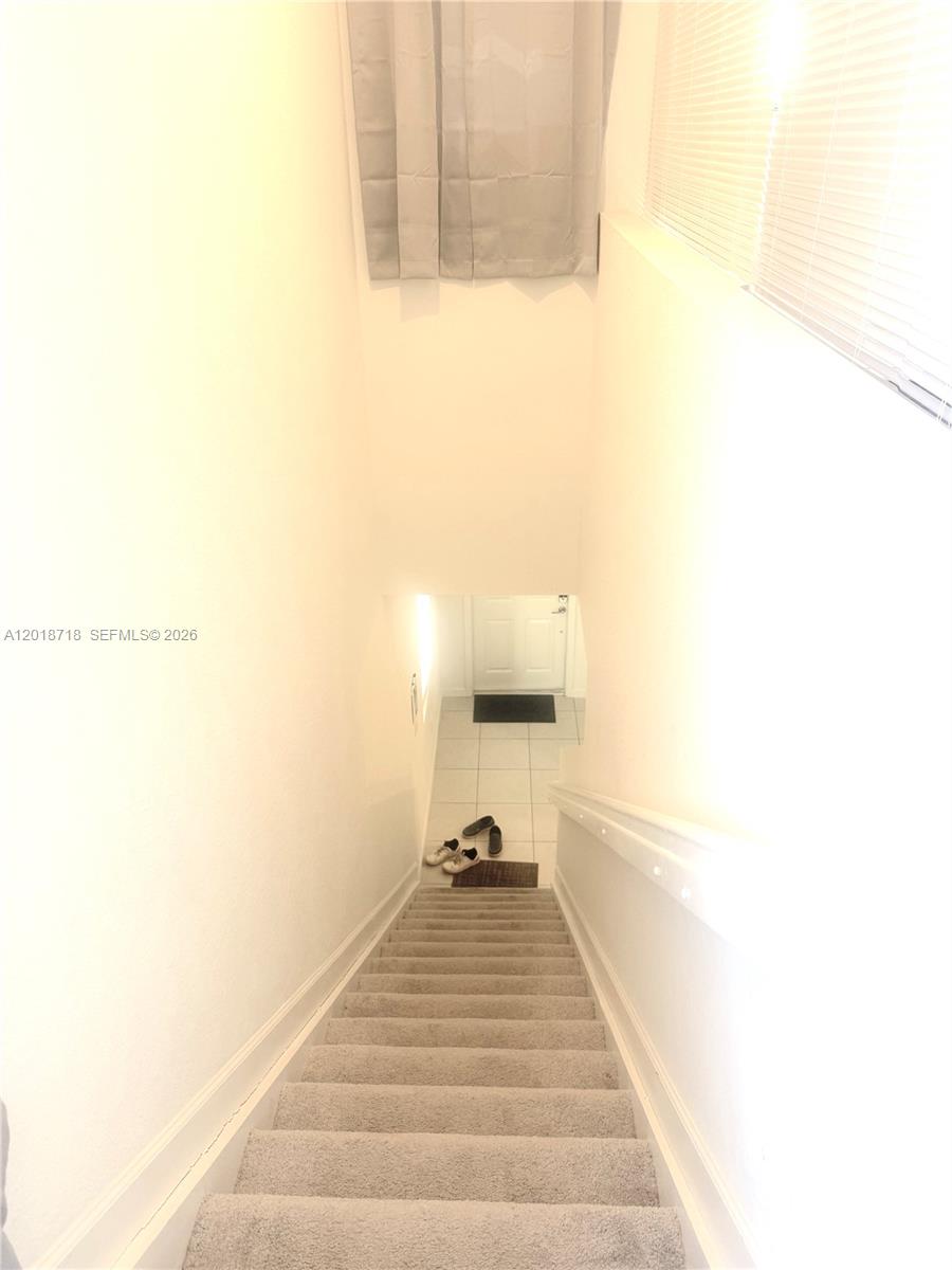 A carpeted staircase leads down to a tiled entryway with a white door — 4941 Oakmont Dr # 5838, Dania Beach FL 33312, DANIA BEACH, FL