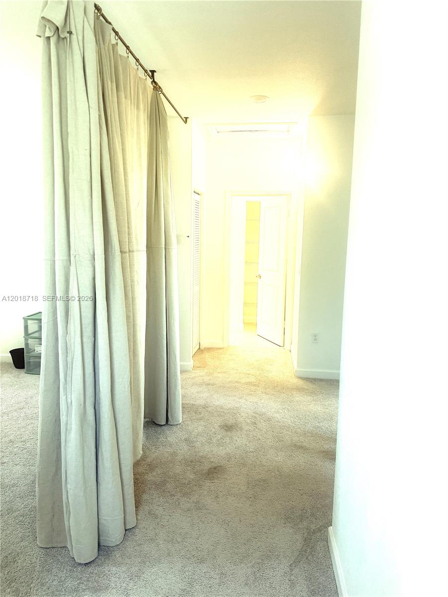 A carpeted room features a floor-to-ceiling curtain divider and a doorway leading to a hallway — 4941 Oakmont Dr # 5838, Dania Beach FL 33312, DANIA BEACH, FL