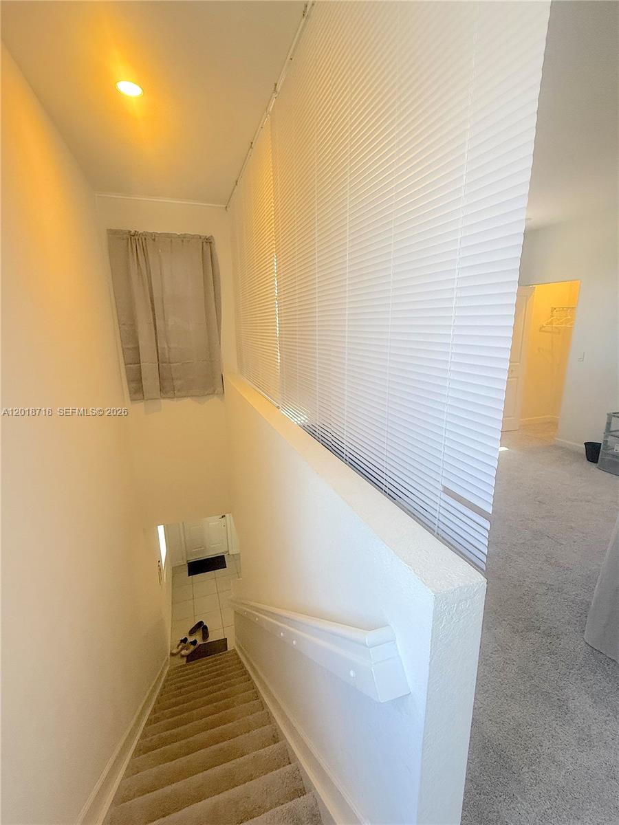 A carpeted staircase leads down to a tiled entryway next to a carpeted upper landing — 4941 Oakmont Dr # 5838, Dania Beach FL 33312, DANIA BEACH, FL