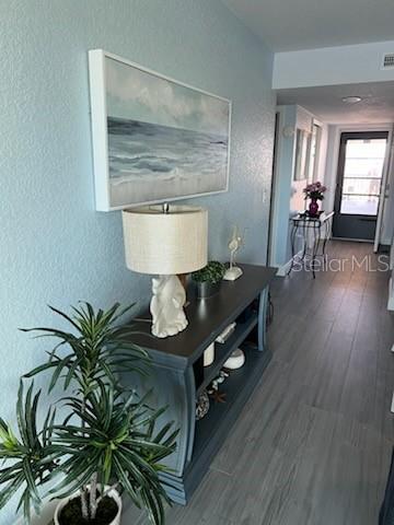 A hallway features a dark console table with a lamp and coastal art against blue walls — 8150 BRENT STREET UNIT 734, PORT RICHEY, FL