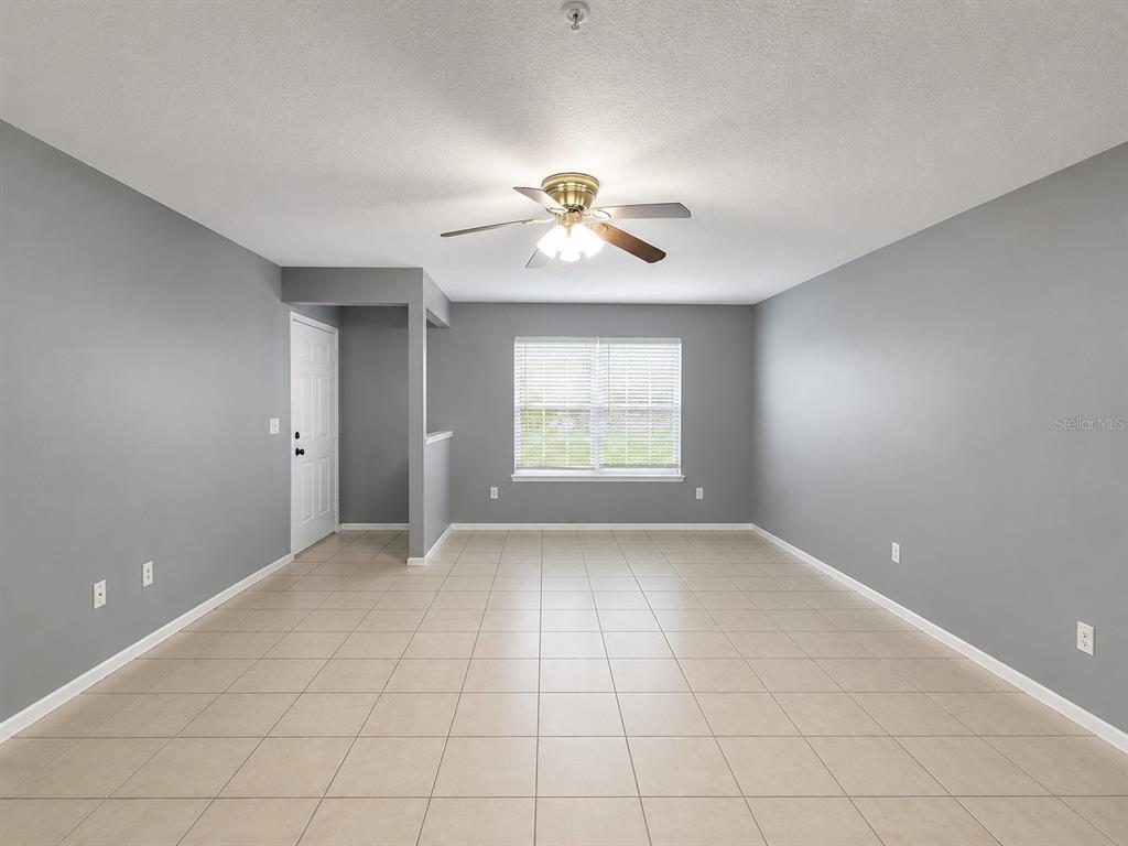 An empty room with gray walls, beige tile flooring, and a ceiling fan — 112 RESERVE CIRCLE UNIT 100, OVIEDO, FL